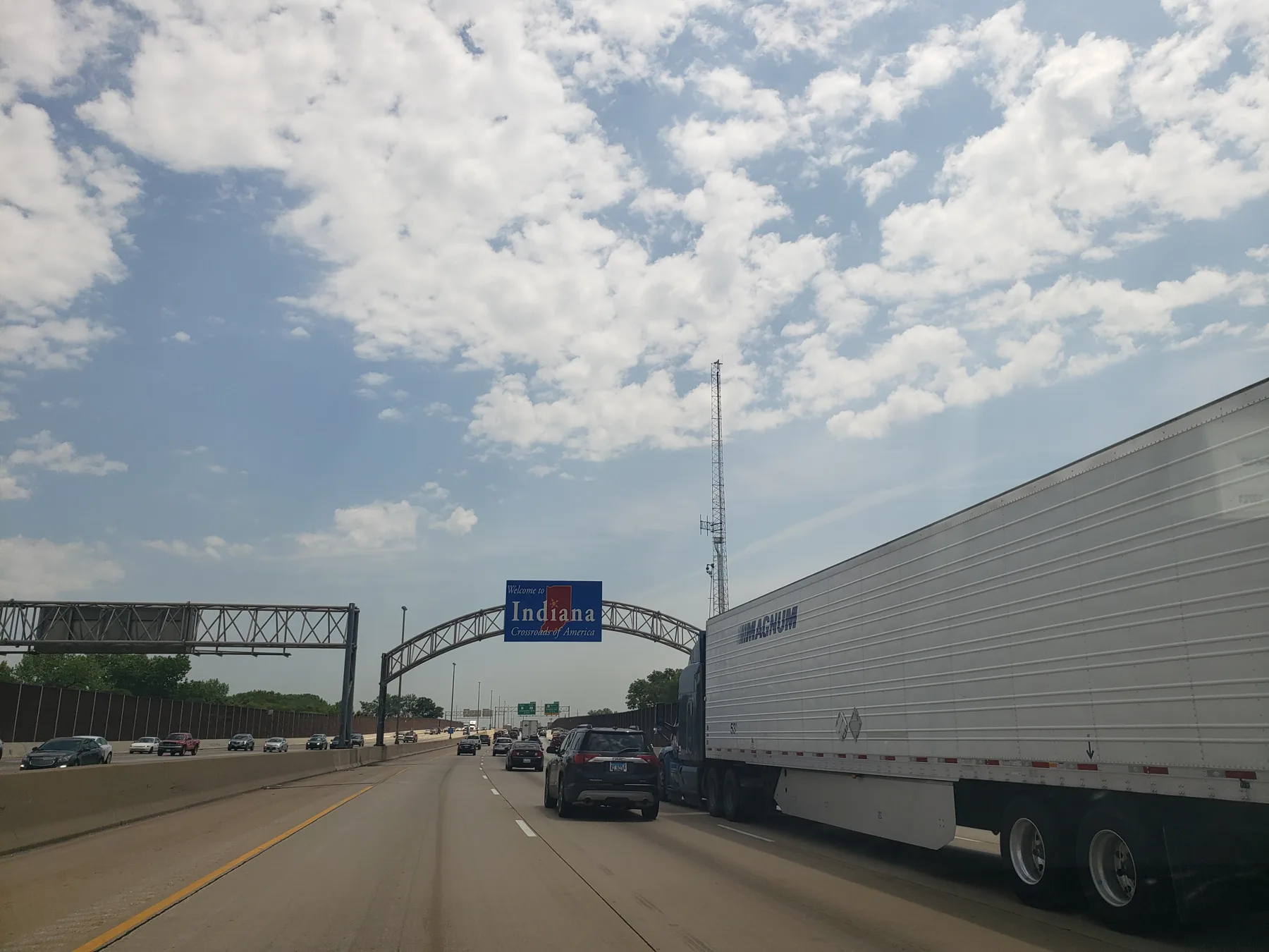 Indiana welcome sign over a multilane highway with cars and a truck