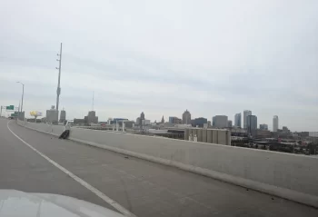 Milwaukee skyline beyond a highway barrier under an overcast sky